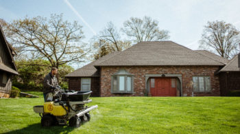 Schendel Lawn & Landscape technician treating lawn in front of a home to prevent fungus.