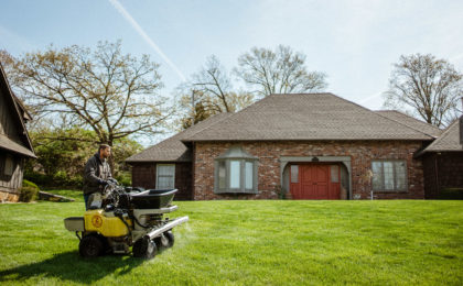 Schendel Lawn & Landscape technician treating lawn in front of a home to prevent fungus.