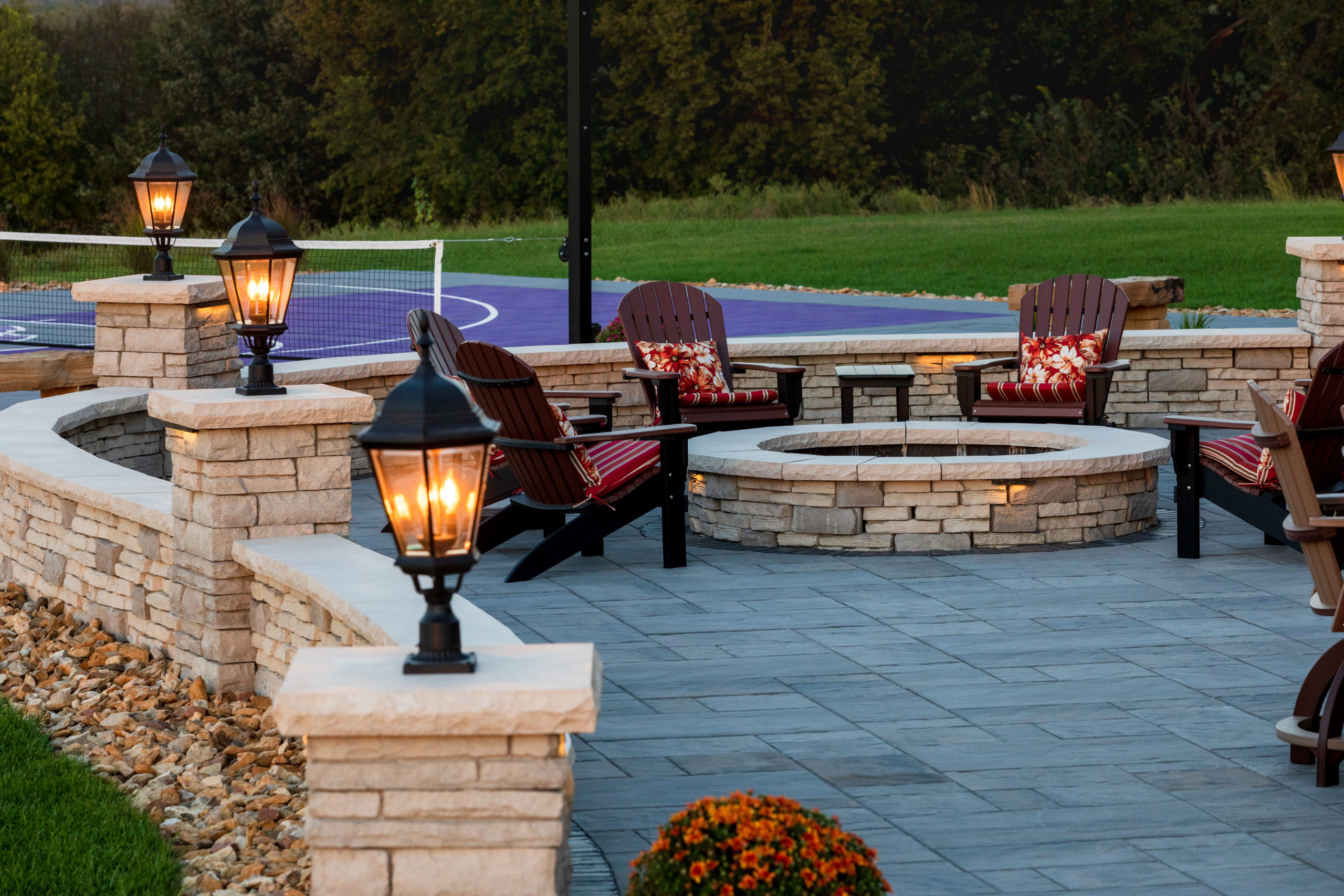 A stone patio space with lighting and a stone fire pit